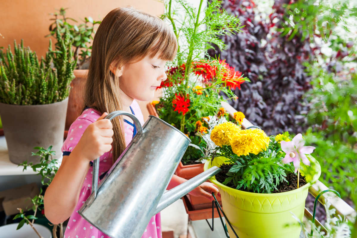 Une petite fille arrose les plantes sur le balcon